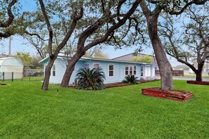 A house with a well-maintained lawn and large trees. - The Lazy Oak Retreat (Rockport)