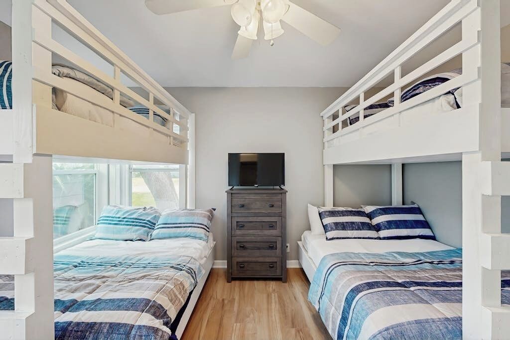 A room with bunk beds, a dresser, and a television.
