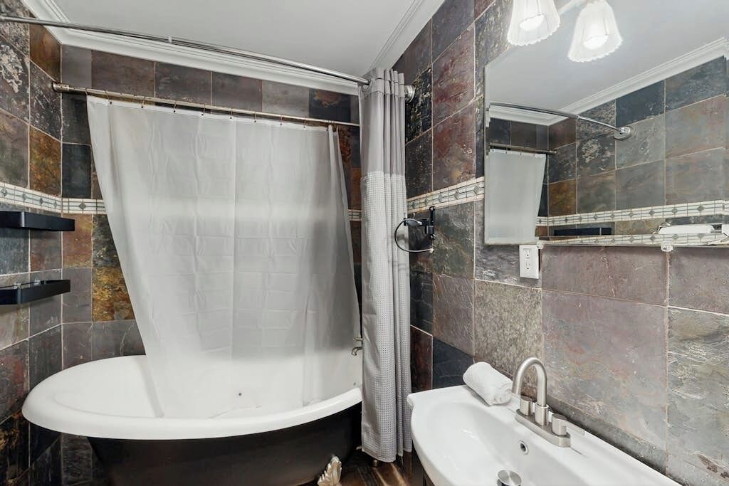 Un bagno con una vasca, un lavandino e una tenda da doccia.