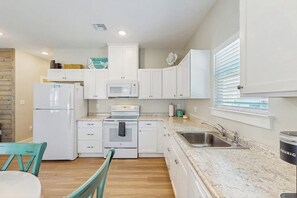 A modern kitchen with white cabinetry, a stainless steel sink, and a built-in oven. - Rockport Oasis Retreat (Rockport)