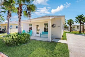 A single-story building with a covered porch, palm trees, and a clear sky. - Rockport Oasis Retreat (Rockport)