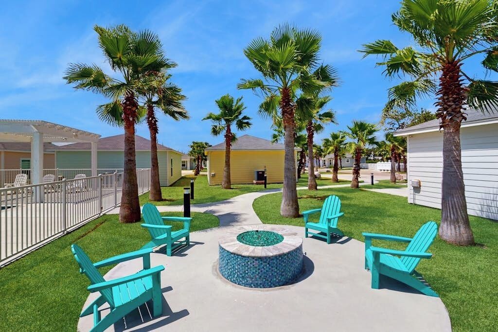 A courtyard with outdoor seating, palm trees, and a circular fire pit.