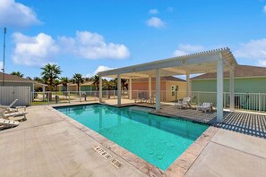 A swimming pool with a covered area, lounge chairs, and a clear sky. - Rockport Oasis Retreat (Rockport)
