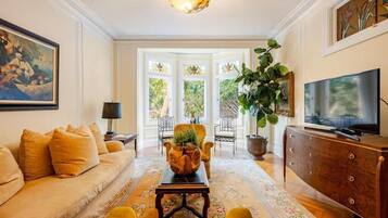 A living room with a sofa, a coffee table, a television, and a large plant.