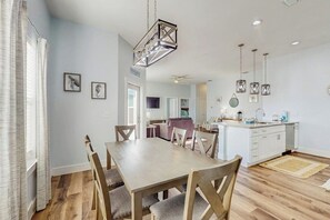 A modern kitchen with a central island, wooden dining table, and chairs. - Stay Anchored Rockport (Rockport)