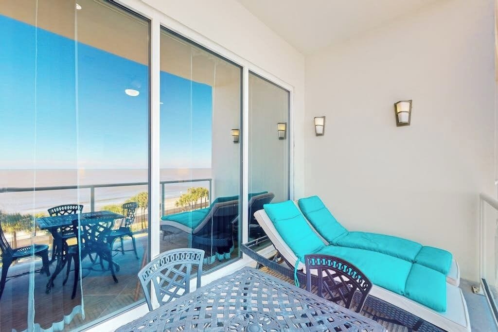 A balcony with a glass door, outdoor furniture, and a view of the landscape.