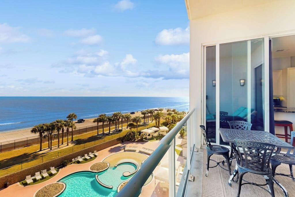 Un balcon avec vue sur une plage et une piscine.