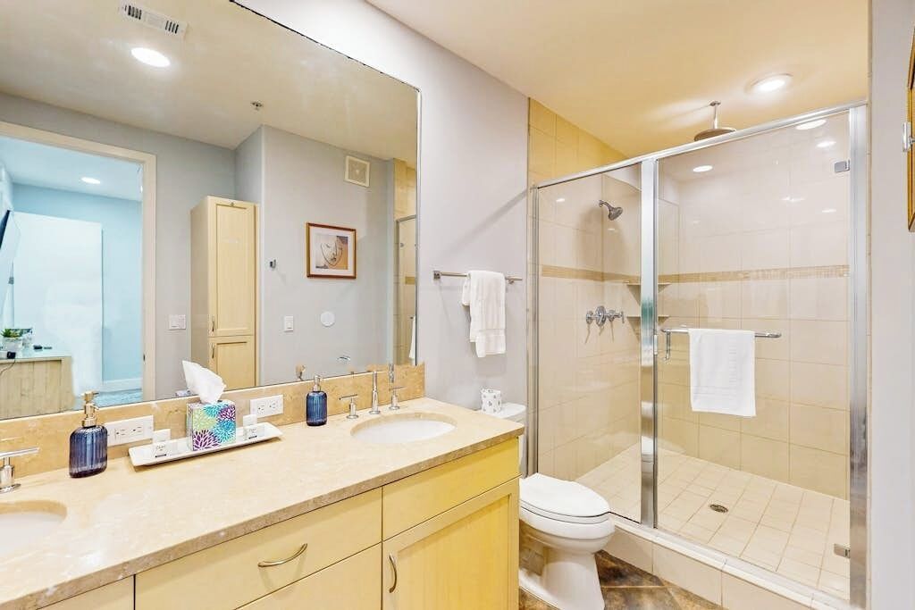 A bathroom with a glass-enclosed shower, a sink with a mirror, and a toilet.