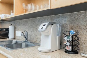 A kitchen with a coffee maker, a water dispenser, and a coffee pod holder. - Emerald By The Sea #603 (Galveston)