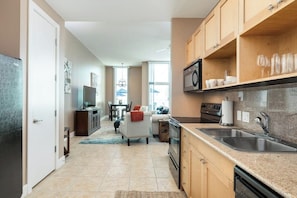 A modern kitchen with granite countertops, stainless steel appliances, and wooden cabinetry. - Emerald By The Sea #603 (Galveston)