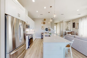 A modern kitchen with a large island, stainless steel appliances, and pendant lighting.