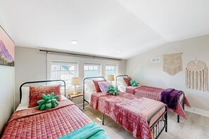Un dormitorio con cuatro camas, un ventanal grande y decoración en las paredes.