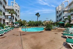 Ein Hotelpoolbereich mit mehreren Liegestühlen und einem zentralen Schwimmbecken.