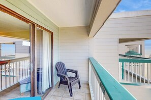 Ein Balkon mit einem Stuhl, einer Glastür und Blick ins Innere des Gebäudes.