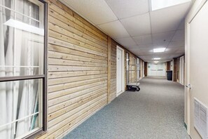 Ein Korridor mit Holzwandverkleidung, Teppichboden und einem Wagen im Hintergrund.