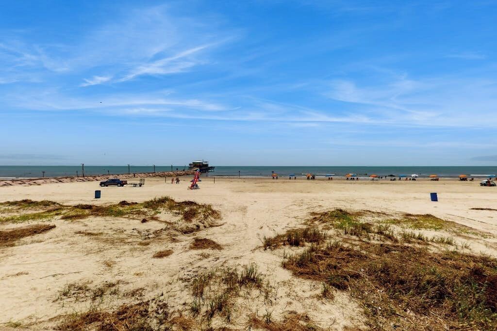 En strand med sandklitter, et redderfyr og strandparasoller.