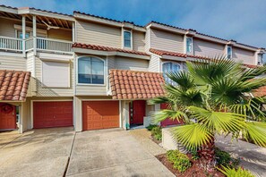 A residential building with a two-story structure, a balcony on the upper floor, and a red door. - Seagull Cove - Waterfront, Bay Views & Garage (Galveston)