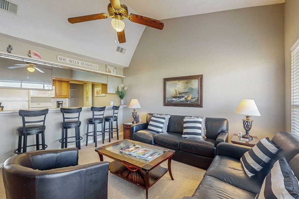 A living room with a sofa, chairs, a coffee table, and a ceiling fan.