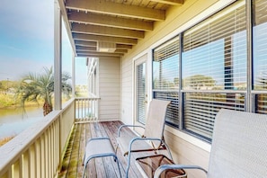 A covered porch with a view of a body of water, wooden deck, and metal chairs. - Seagull Cove - Waterfront, Bay Views & Garage (Galveston)