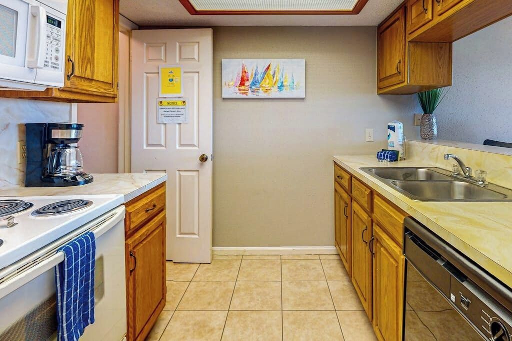 A compact kitchen with a microwave, coffee maker, stove, and dishwasher.