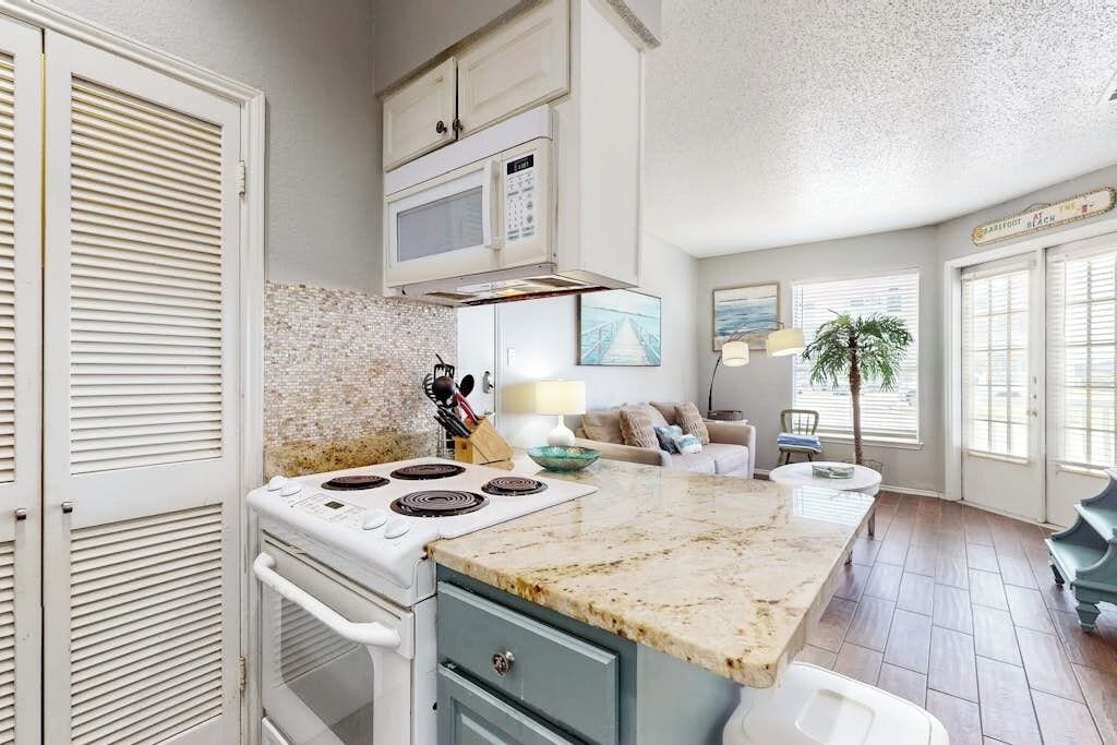 A kitchen with a stove, microwave, and a dining area with a table and chairs.