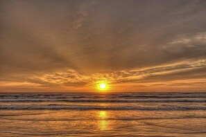 Un coucher de soleil sur l’océan, les vagues reflétant la couleur du ciel.