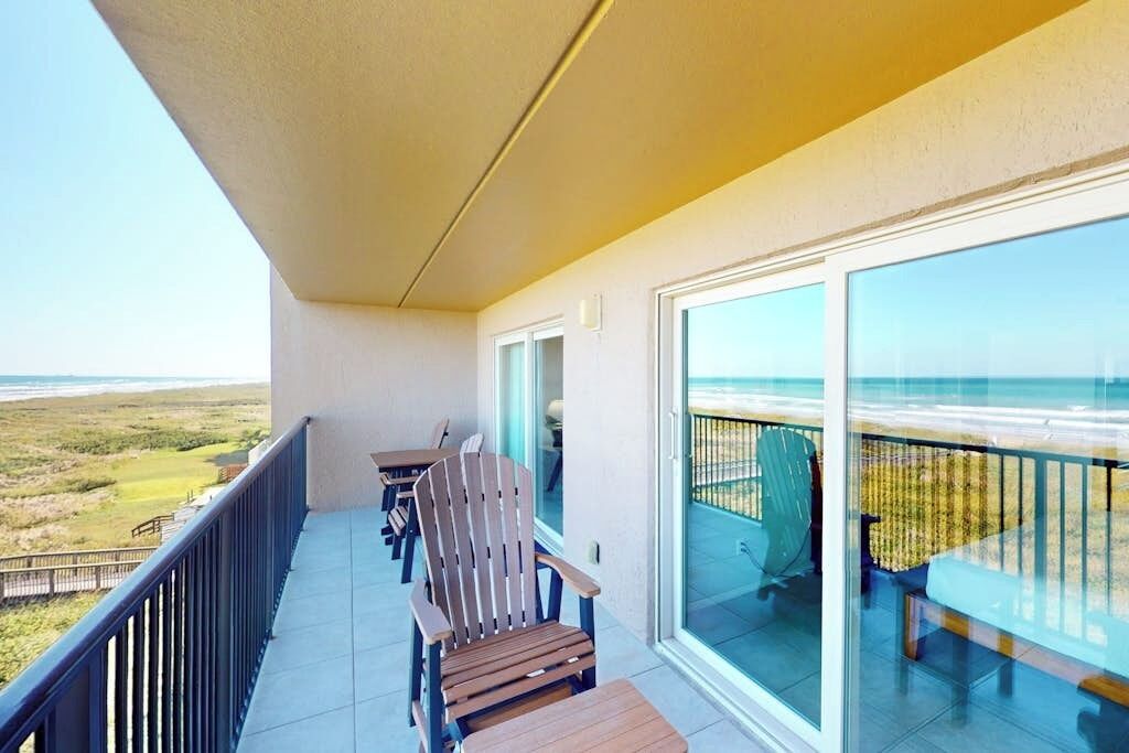Un balcon avec vue sur la plage, une table et deux chaises.