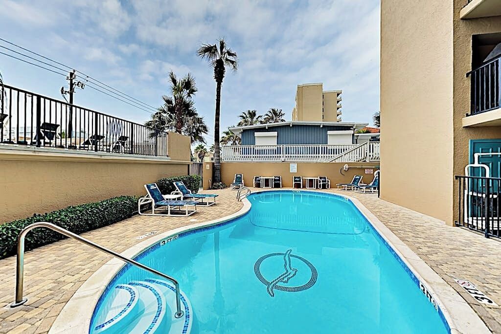 Una piscina con lettini e una palma.