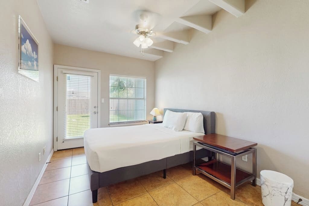 A bedroom with a bed, bedside table, and a ceiling fan.