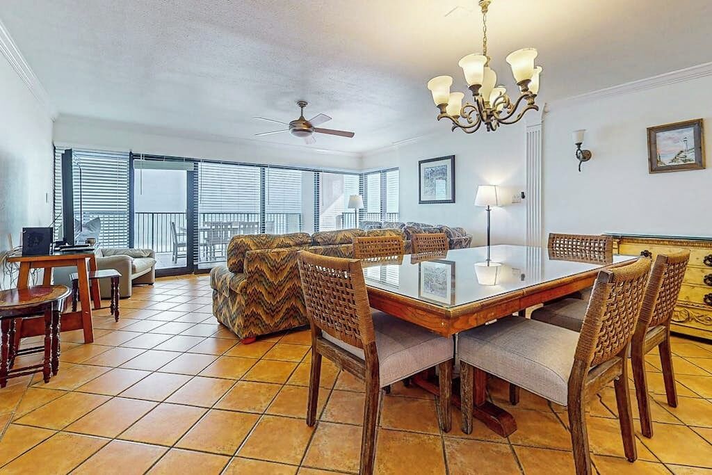 Un vaste espace de vie comprenant une table à manger, des chaises, un canapé et un ventilateur de plafond.
