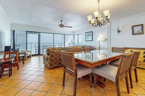 Un vaste espace de vie comprenant une table à manger, des chaises, un canapé et un ventilateur de plafond.