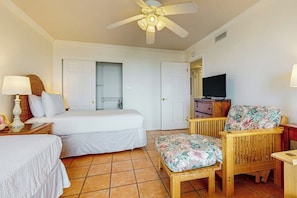 A hotel room with a bed, a chair, a television, and a ceiling fan. - Ocean Vista Condominiums #1101 (South Padre Island)
