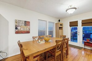 A dining area with a wooden table, chairs, a bowl, and a ceiling light fixture. - The Yellow Pelican - Bay Views, Steps to the Sand (Jamaica Beach)