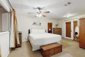 A bedroom with a bed, a wooden bench, a ceiling fan, a dresser, and a mirror. - The Yellow Pelican - Bay Views, Steps to the Sand (Jamaica Beach)