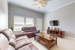 Ein Wohnzimmer mit einer Couch, einem Couchtisch, einem Fernseher und einem Schrank.