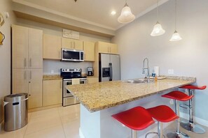 Eine moderne Küche mit Granit Arbeitsplatten, Edelstahlgeräten und roten Barhocker.