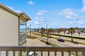 Ein Balkon mit Blick auf einen Parkplatz und den Strand sowie das Meer.