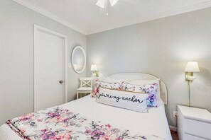 Ein Schlafzimmer mit einem Bett, einem Nachttisch, einem Spiegel und zwei Wandlampen.