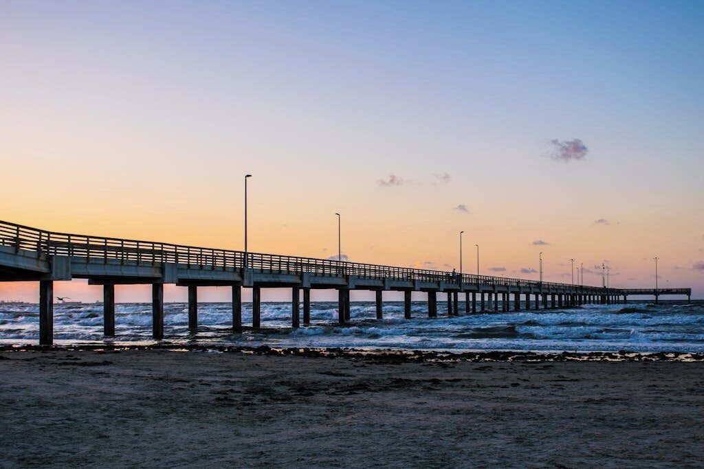 Eine Mole, die sich ins Meer erstreckt, mit blauem Himmel darüber.