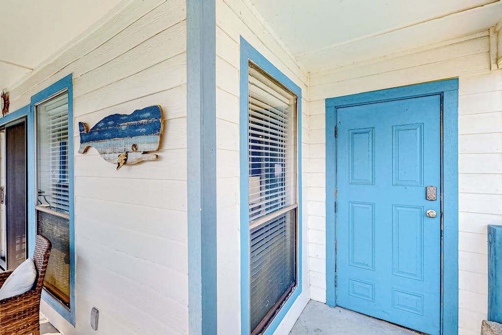 Una casa con una puerta azul y una ventana con persianas.