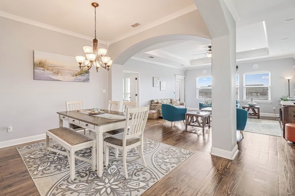 A spacious dining area with a chandelier, a large painting, and a patterned rug.