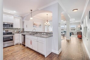 A kitchen with white cabinets, granite countertops, and stainless steel appliances. - The Blue Shell - Pool, Big Deck & Dog-Friendly (Port Aransas)