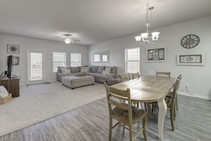 A spacious living area with a sofa set, a dining table with chairs, and a chandelier. - Compass Condominiums A7 (Corpus Christi)