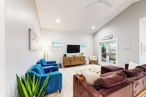 A living room with a sofa, a television, and a plant. - Martinis & Marlin - Heated Pool (Port Aransas)