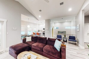 Ein modernes Wohnzimmer mit einer Eckcouch, einem Couchtisch und einem Essbereich im Hintergrund.