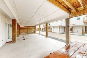 An open-plan indoor space with a concrete floor, wooden beams, and a slatted wooden partition. - Martinis & Marlin - Heated Pool (Port Aransas)
