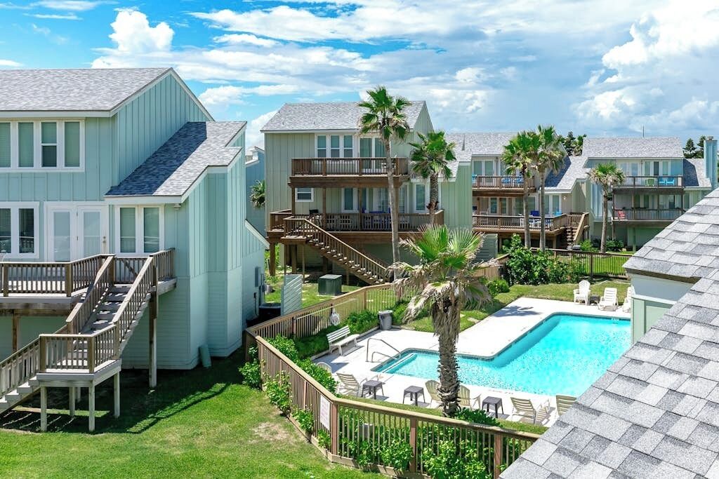 Une propriété située en bord de mer, comprenant plusieurs bâtiments, une piscine et un escalier menant aux étages supérieurs.