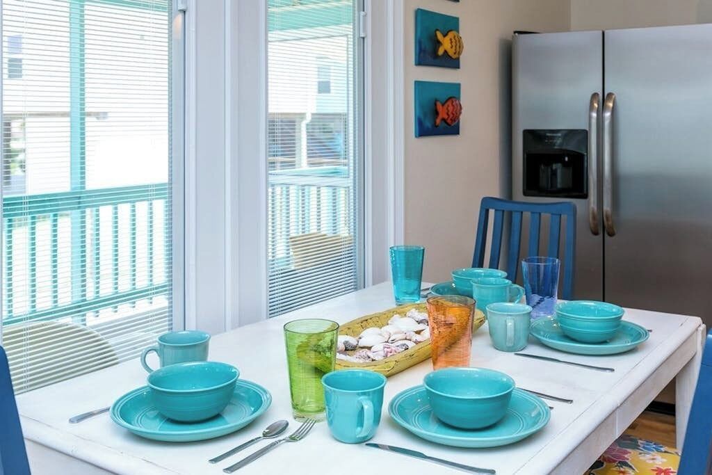 A dining area with a white table set with blue dishes and a tray of snacks.