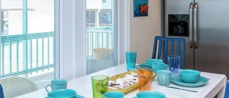 Un comedor con una mesa blanca dispuesta con vajilla azul y una bandeja de aperitivos.