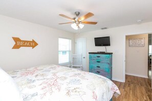 A bedroom with a bed, a ceiling fan, a television, a dresser, and a door with a sign. - Rockport Getaway - Screened Porch, Near the Beach (Rockport)